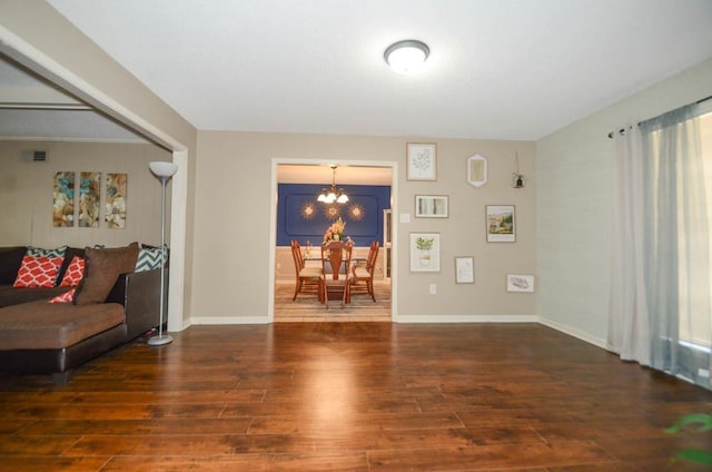 living area with baseboards, an inviting chandelier, and wood finished floors