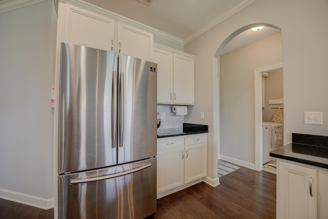 kitchen featuring backsplash, freestanding refrigerator, arched walkways, separate washer and dryer, and dark wood-style floors