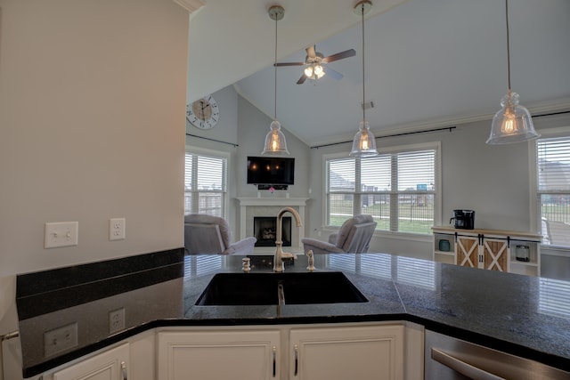 kitchen with a fireplace, a ceiling fan, white cabinets, a sink, and open floor plan