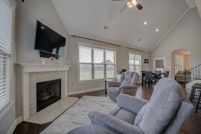 living area with ceiling fan, arched walkways, wood finished floors, and a fireplace