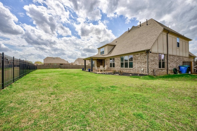 rear view of house with a yard, brick siding, a fenced backyard, and a patio