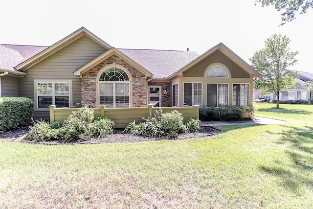 rear view of house with roof with shingles and a lawn