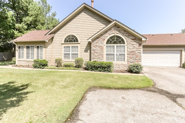 view of front of property with a shingled roof, aphalt driveway, a front yard, and a garage