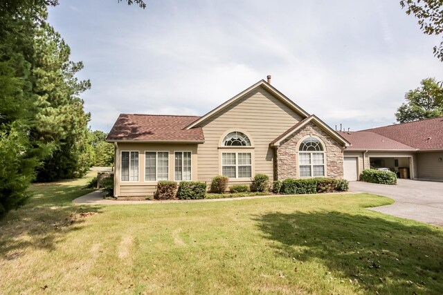 view of front of house with a garage, stone siding, a front lawn, a shingled roof, and driveway