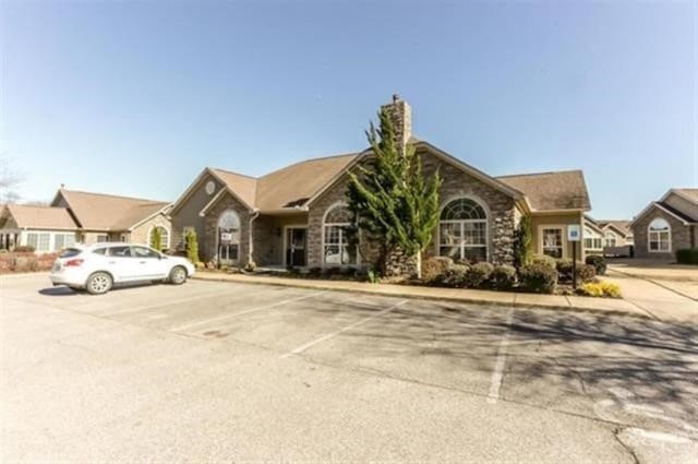 ranch-style house with uncovered parking and stone siding