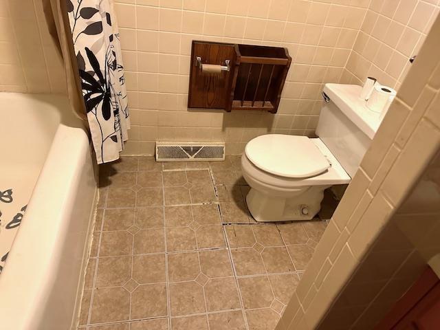 bathroom with visible vents, toilet, tile patterned flooring, and tile walls