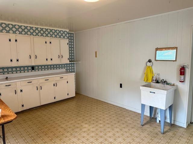 kitchen featuring white cabinets, light countertops, ornamental molding, and light floors