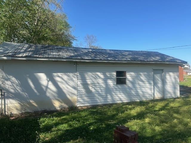 view of home's exterior featuring metal roof, an outdoor structure, and a lawn