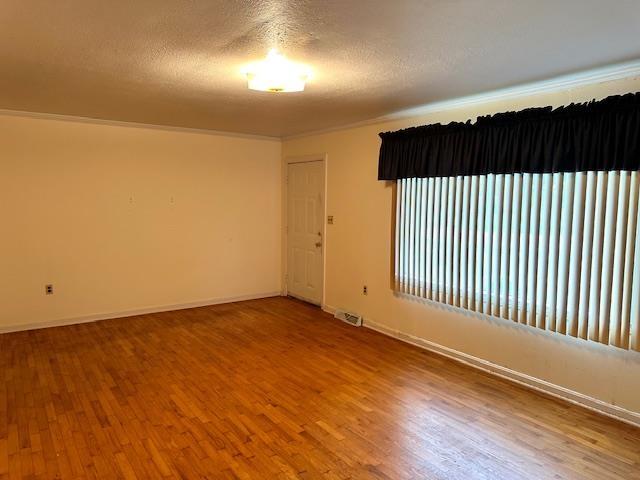 spare room featuring a textured ceiling, wood finished floors, and visible vents