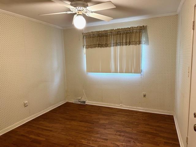 empty room with visible vents, wallpapered walls, ornamental molding, and dark wood finished floors