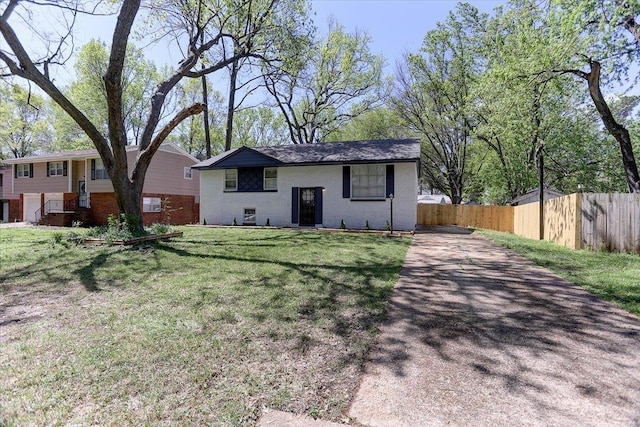 bi-level home with aphalt driveway, a front yard, fence, and brick siding