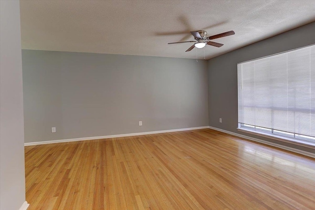 empty room with light wood-style floors, baseboards, a ceiling fan, and a textured ceiling