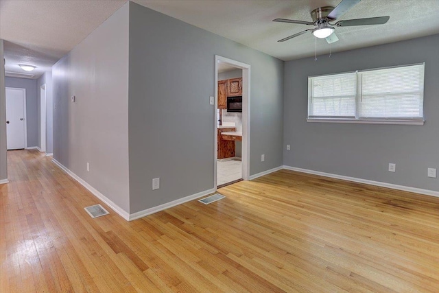 spare room featuring visible vents, ceiling fan, light wood finished floors, and baseboards