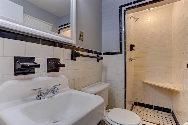 full bathroom featuring toilet, a stall shower, a sink, and tile walls