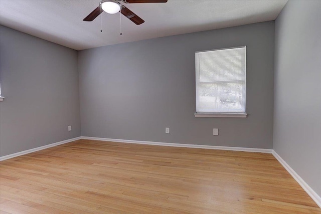 unfurnished room with ceiling fan, light wood finished floors, and baseboards