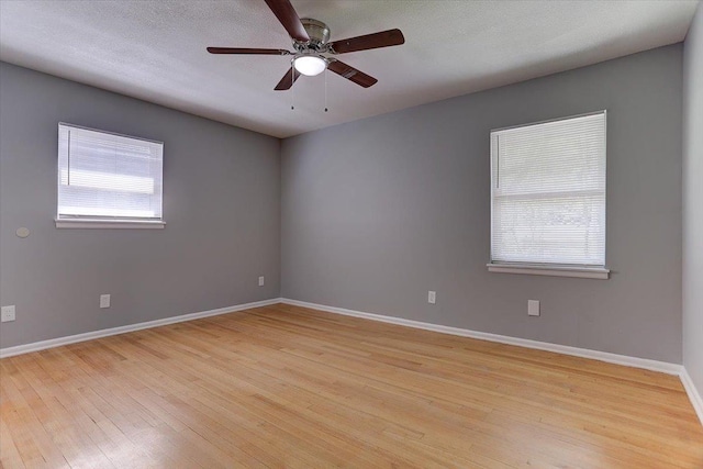spare room featuring a textured ceiling, baseboards, light wood-type flooring, and a ceiling fan