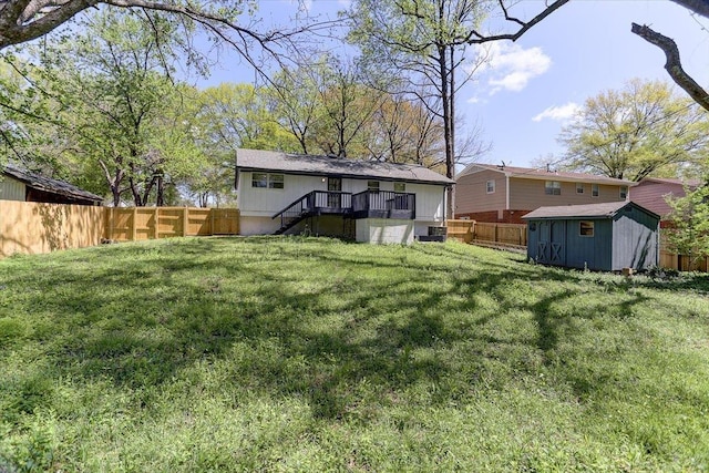 back of house featuring a yard, a fenced backyard, a storage unit, and an outdoor structure