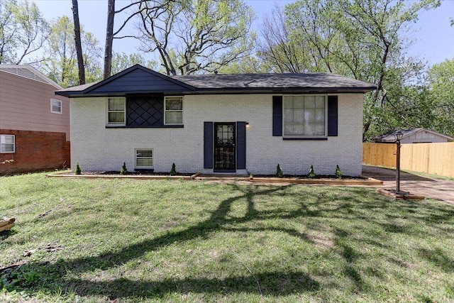 bi-level home with fence, a front lawn, and brick siding