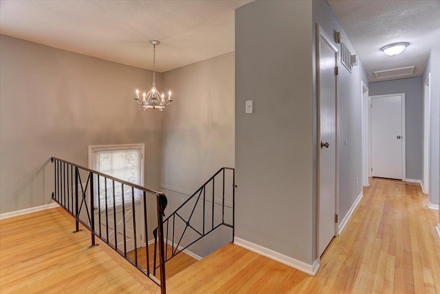 stairway with baseboards, wood finished floors, and a textured ceiling