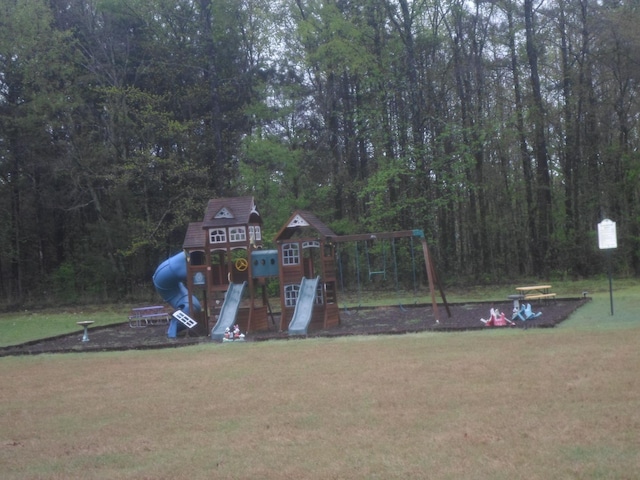view of property's community featuring a yard, a wooded view, a carport, and playground community