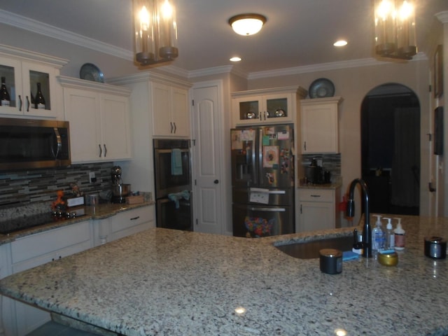 kitchen with double oven, refrigerator with ice dispenser, stainless steel microwave, a sink, and black electric stovetop