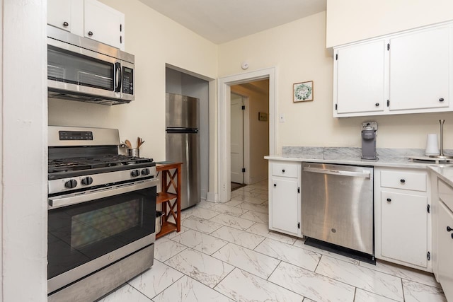 kitchen featuring light stone countertops, marble finish floor, white cabinetry, and appliances with stainless steel finishes