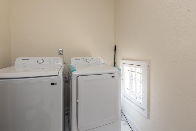 clothes washing area with baseboards, separate washer and dryer, and laundry area