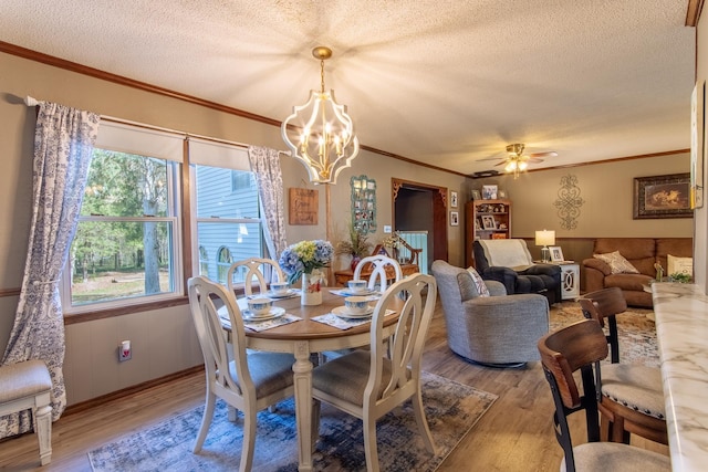 dining space with light wood-style floors, a textured ceiling, and crown molding