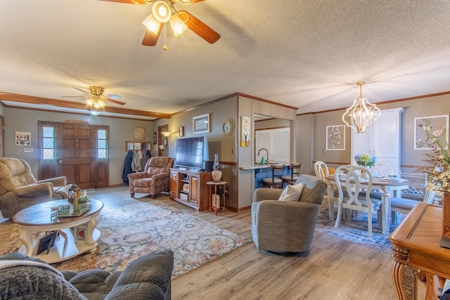 living room with ornamental molding, a textured ceiling, light wood finished floors, and ceiling fan with notable chandelier
