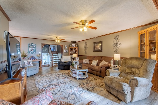 living area featuring crown molding, ceiling fan, a textured ceiling, stairway, and wood finished floors