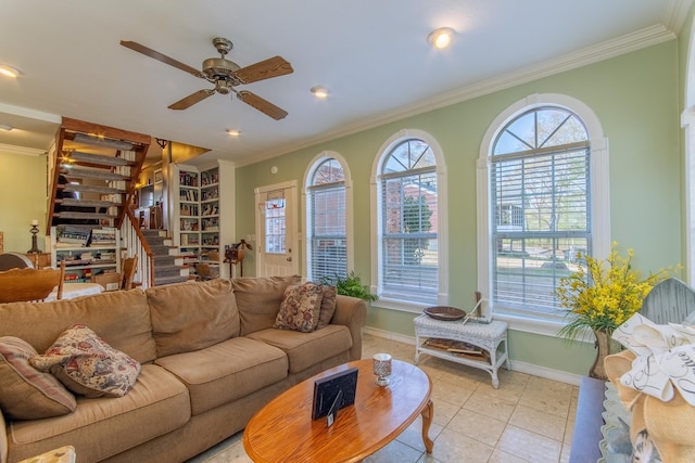 living area featuring light tile patterned floors, baseboards, ceiling fan, crown molding, and stairway