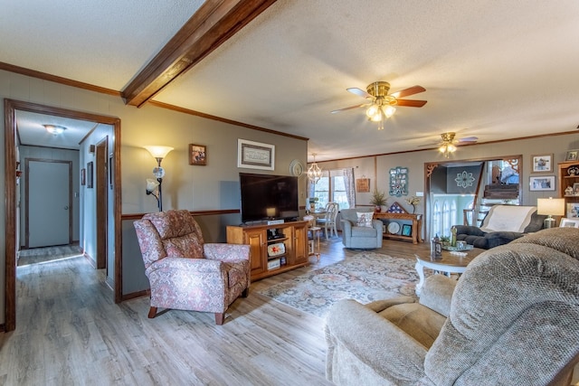 living area featuring ornamental molding, beamed ceiling, light wood-type flooring, and a ceiling fan