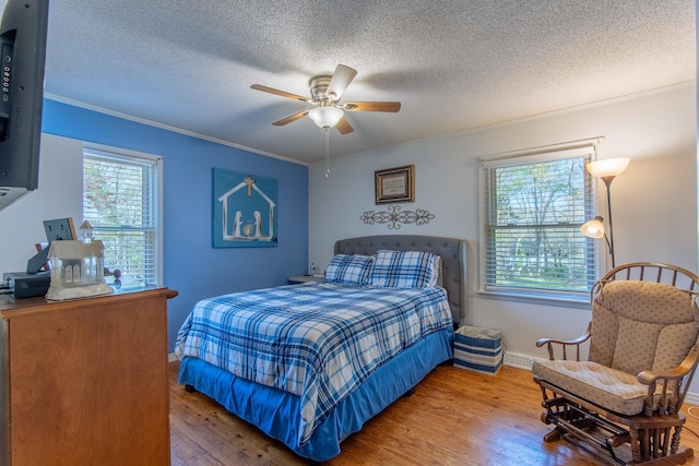 bedroom featuring ornamental molding, multiple windows, and wood finished floors