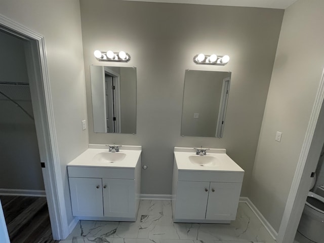 bathroom featuring baseboards, marble finish floor, two vanities, and a sink