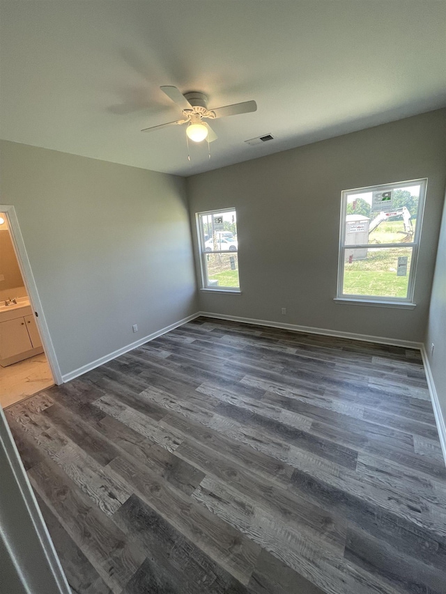spare room with dark wood-style flooring, baseboards, a ceiling fan, and visible vents
