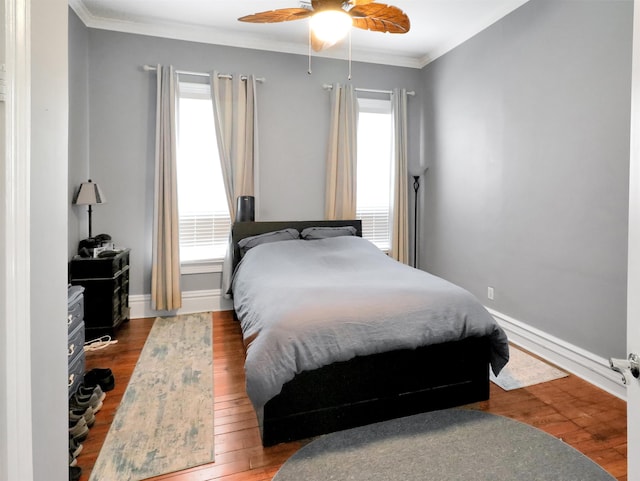 bedroom with crown molding, baseboards, ceiling fan, and hardwood / wood-style flooring