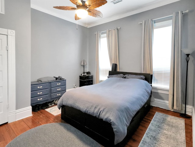 bedroom with baseboards, dark wood-style floors, crown molding, a ceiling fan, and visible vents