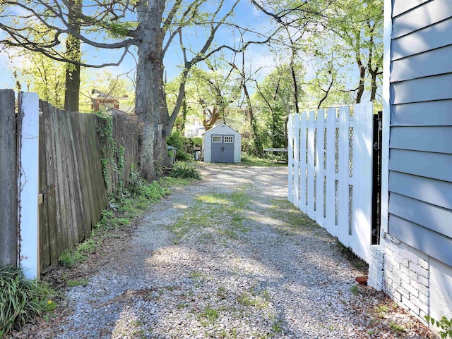 view of yard with an outbuilding, driveway, fence, and a shed