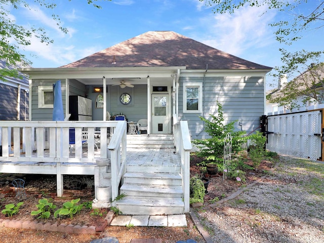 back of house with covered porch, roof with shingles, fence, and ceiling fan