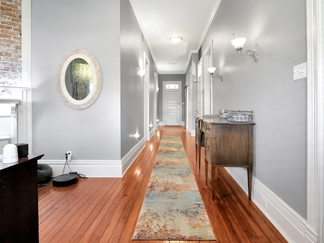 corridor featuring crown molding, wood-type flooring, and baseboards