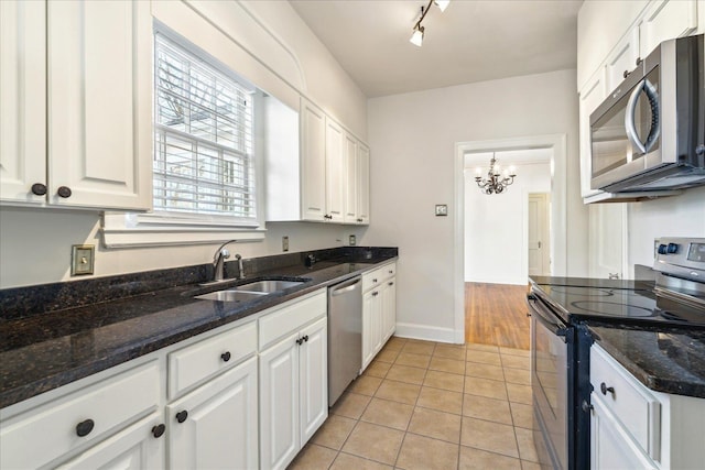 kitchen featuring appliances with stainless steel finishes, light tile patterned floors, a sink, and white cabinetry