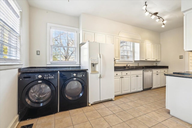 clothes washing area featuring laundry area, light tile patterned floors, a sink, and washing machine and dryer