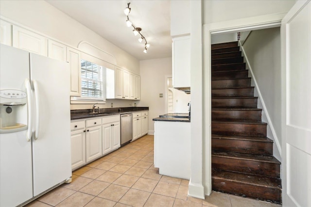 kitchen with white refrigerator with ice dispenser, dark countertops, stainless steel dishwasher, and light tile patterned flooring