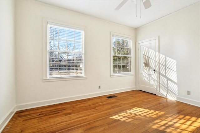 empty room with visible vents, baseboards, a ceiling fan, hardwood / wood-style flooring, and crown molding