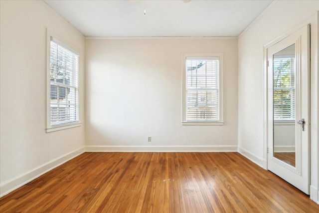 empty room featuring crown molding, light wood-style floors, and a healthy amount of sunlight