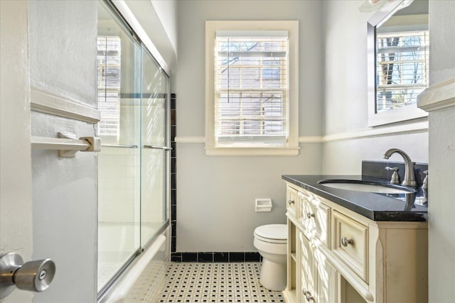 bathroom featuring shower / bath combination with glass door, vanity, baseboards, and toilet