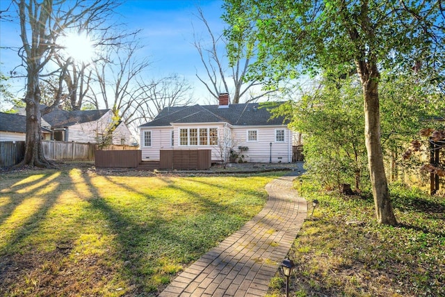 rear view of house with a hot tub, a yard, a chimney, fence, and central air condition unit