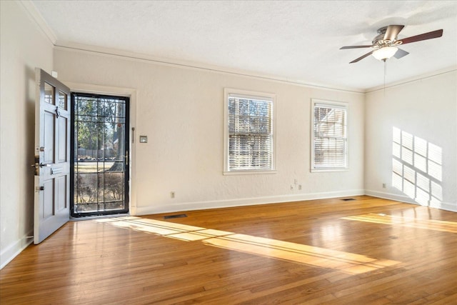 interior space featuring baseboards, ornamental molding, visible vents, hardwood / wood-style floors, and ceiling fan