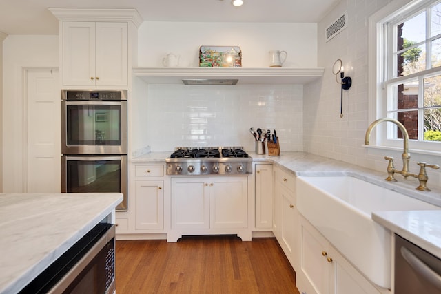 4252 Heatherwood Ln, Memphis, TN 38117 - kitchen with open shelves, appliances with stainless steel finishes, a sink, wood finished floors, and visible vents