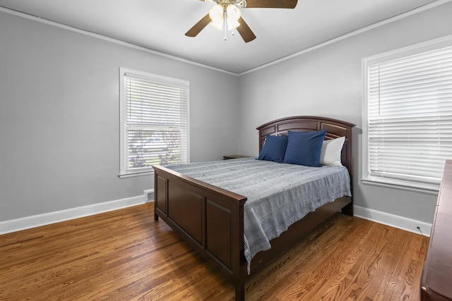 bedroom with crown molding, wood finished floors, and baseboards